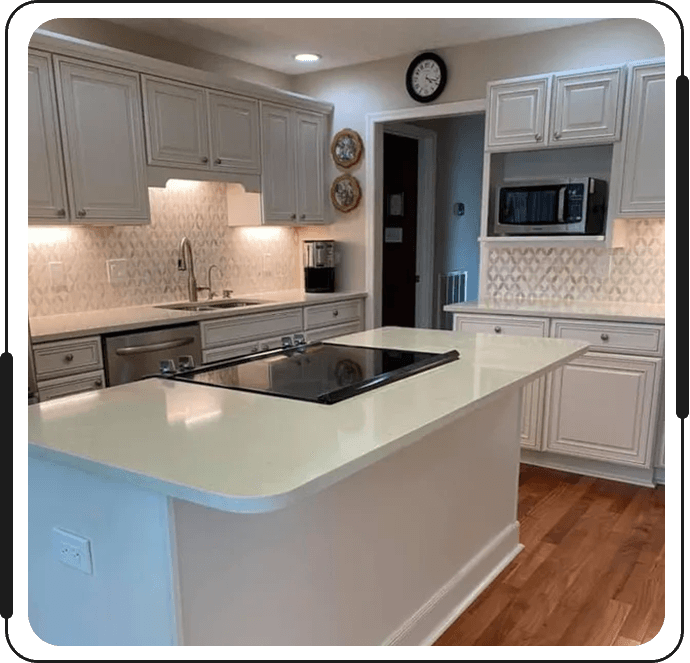 A kitchen with white cabinets and wood floors.