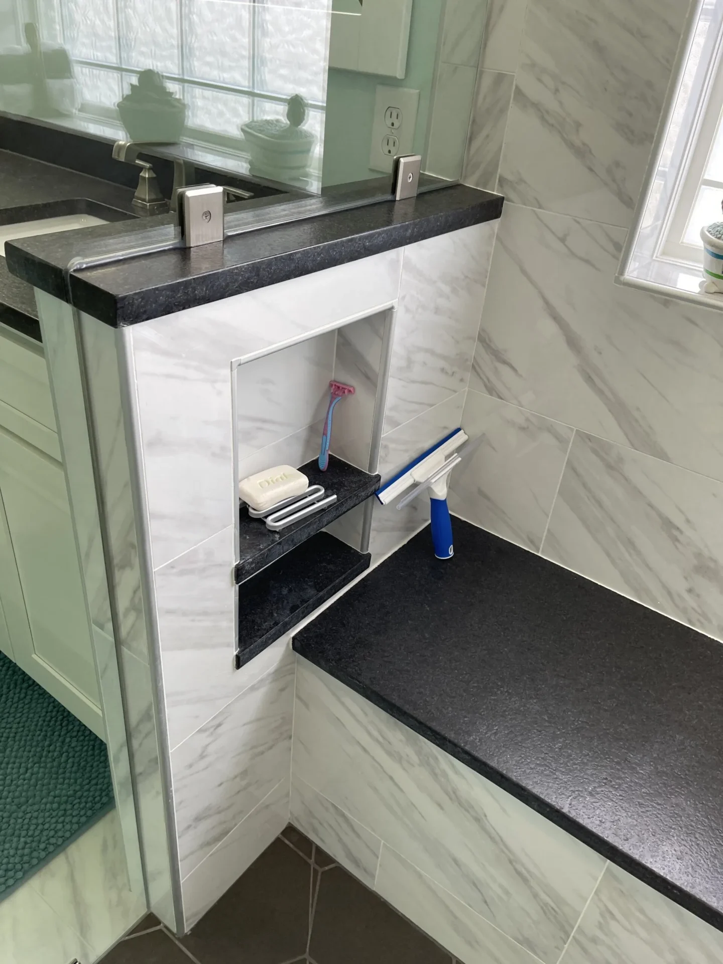 A bathroom with marble walls and white counter tops.