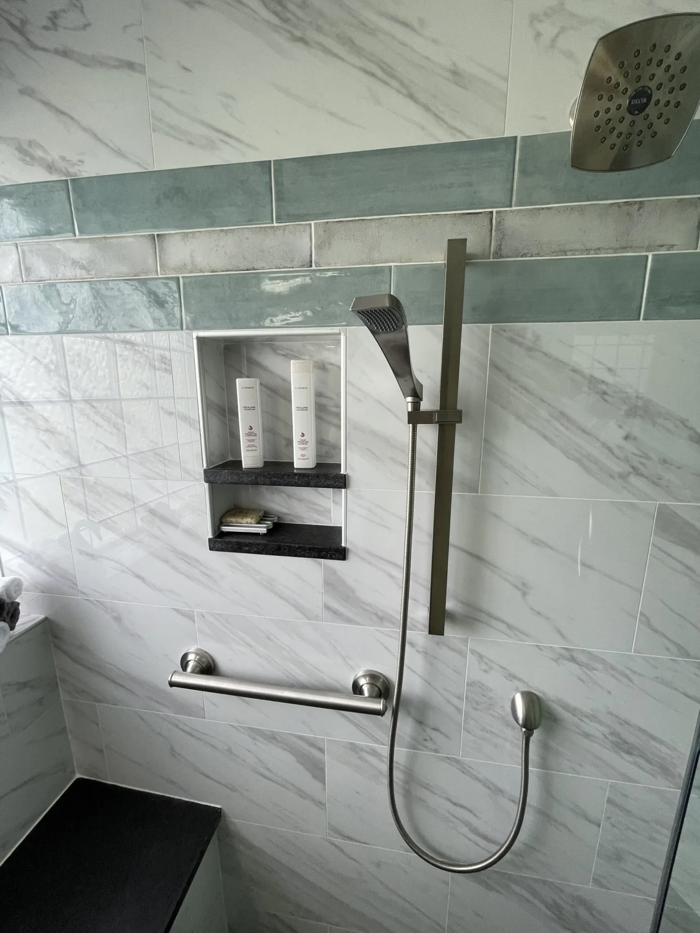 A bathroom with marble walls and a shower.