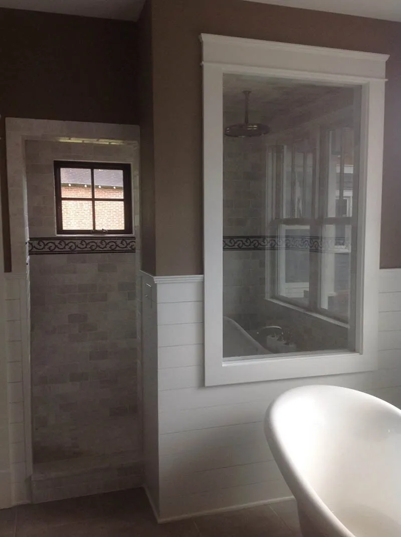 A bathroom with a tub, shower and window.