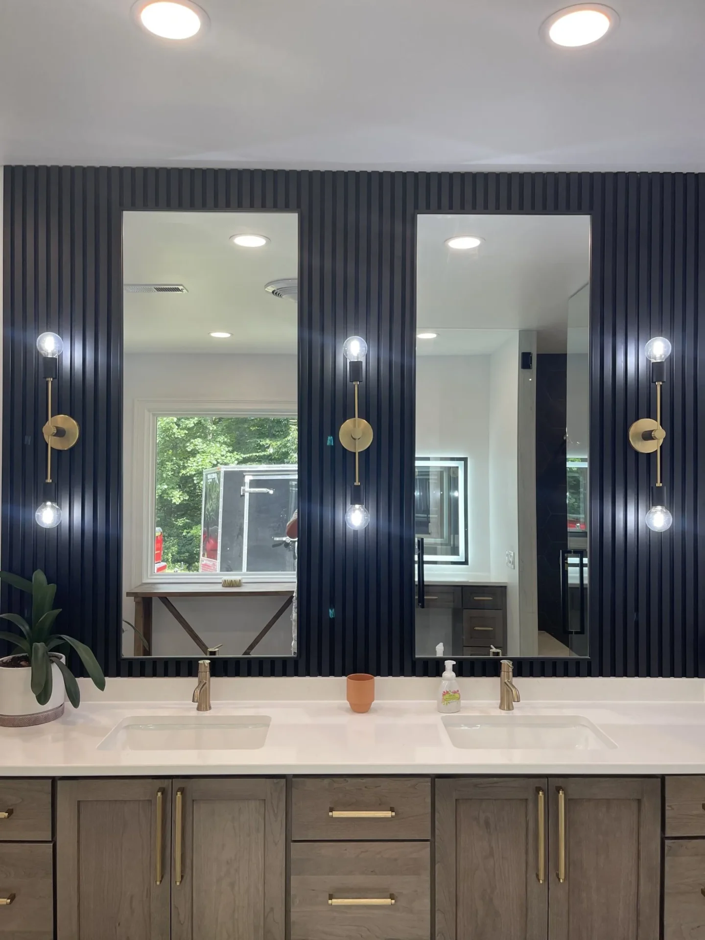 A bathroom with three mirrors and two sinks.